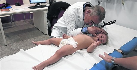 Un médico ausculta a una niña, ayer en el Hospital de Nens de Barcelona.