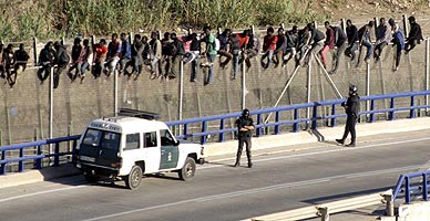 Inmigrantes encaramados a la valla de Melilla, este martes.