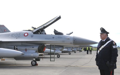 Un policía italiano monta guardia junto a aviones daneses F-16 en la base aérea de la OTAN en Sigonela, en la isla de Sicilia, Italia. 
