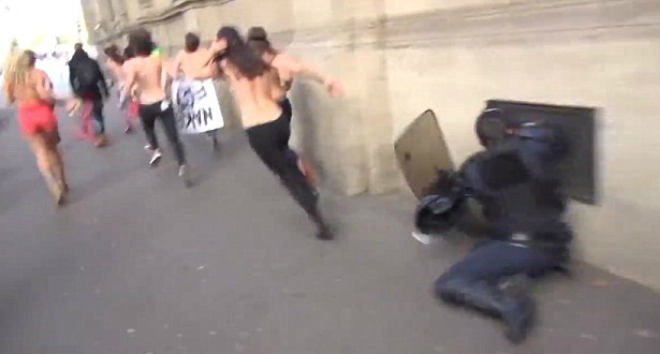 Un policía choca contra la pared al intentar interceptar a una activista de Femen, en París, este lunes. 