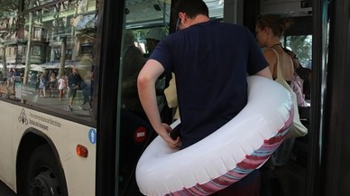 Un hombre con flotador incorporado trata de entrar en un bus lleno en el paseo de Joan de Borbó.