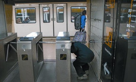 Un hombre pasa, sin validar billete alguno, por debajo de un torniquete de la estación de metro de Jaume I de la L-4, ayer.