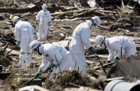 Miembros de la policía con trajes especiales inspeccionan terrenos arrasados en Minamisoma, en el departamento de Fukushima.