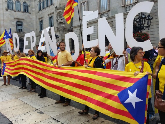 Simpatizantes de la ANC y Òmnium Cultural, tras una 'senyera', en la plaza Sant Jaume, este sábado.