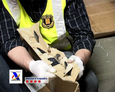 Un agente de los Mossos muestra los pliegues de la caja de cartón donde estaba oculta la heroína. 