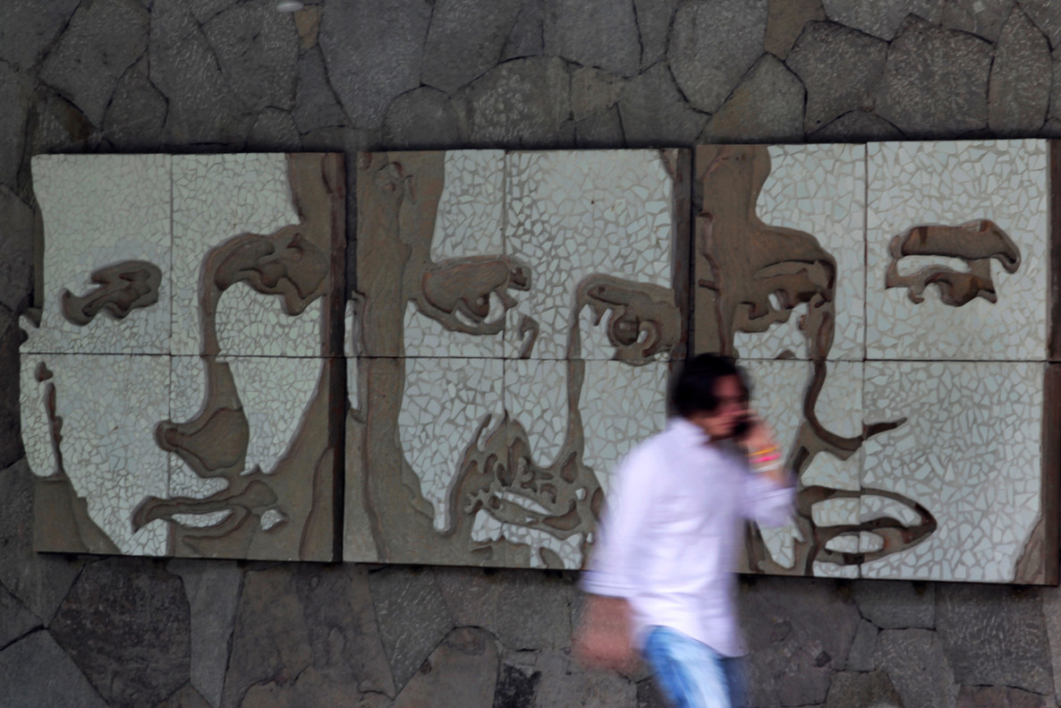 A man walks past portraits of three of the six murdered Jesuit priests, in San Salvador