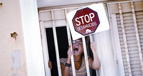 Una mujer protesta desde la ventana de una casa durante un acto de desahucio, en junio del 2011, en Madrid.
