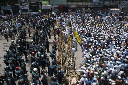 Cientos de islamistas, a la derecha, que bloquean una calle en Dacca, se enfrentran a la policía, el domingo.