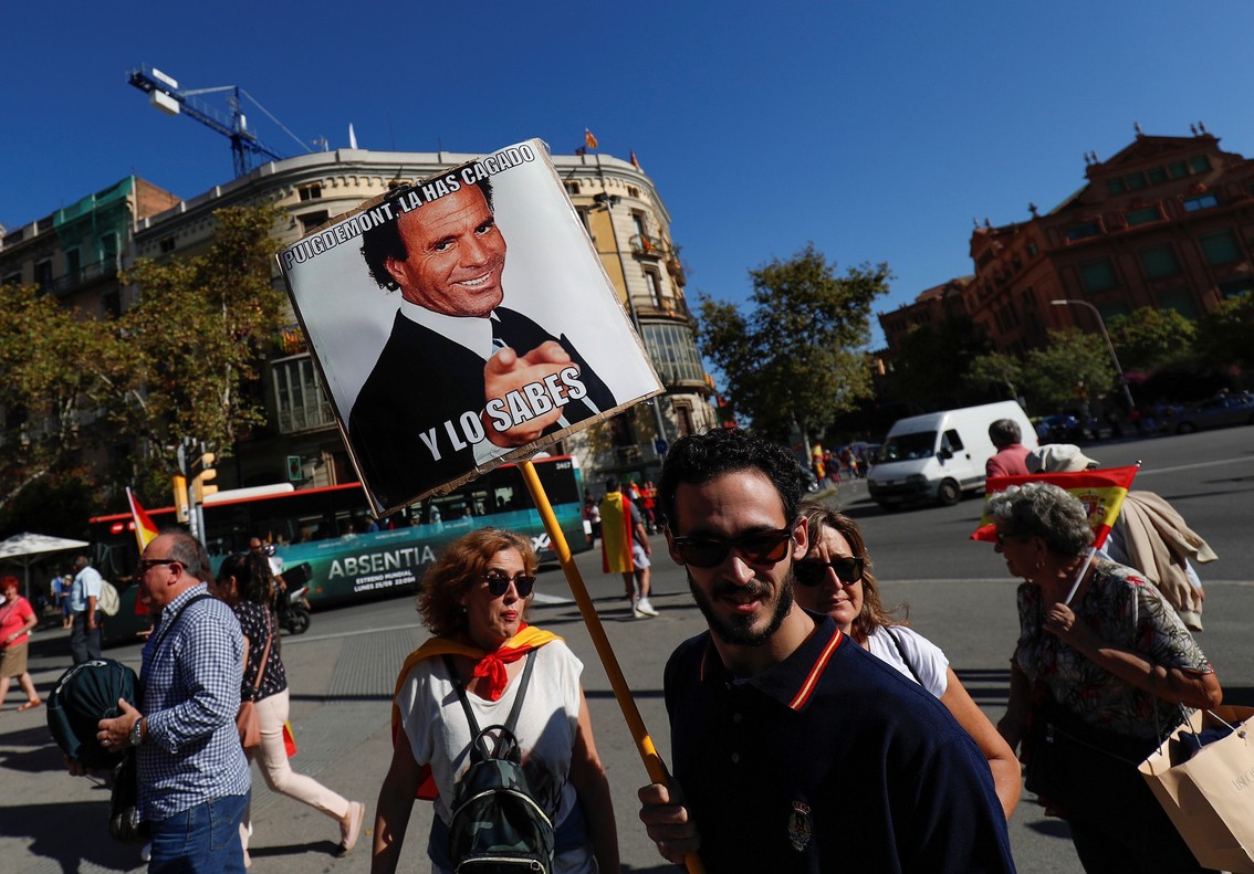 A man carries a sign depicting Spanish singer Julio Iglesias which reads Puigdemont you messed up and you know it as demonstrators gathered for a pro-union demonstration organised by the Catalan Civil Society organisation in Barcelona