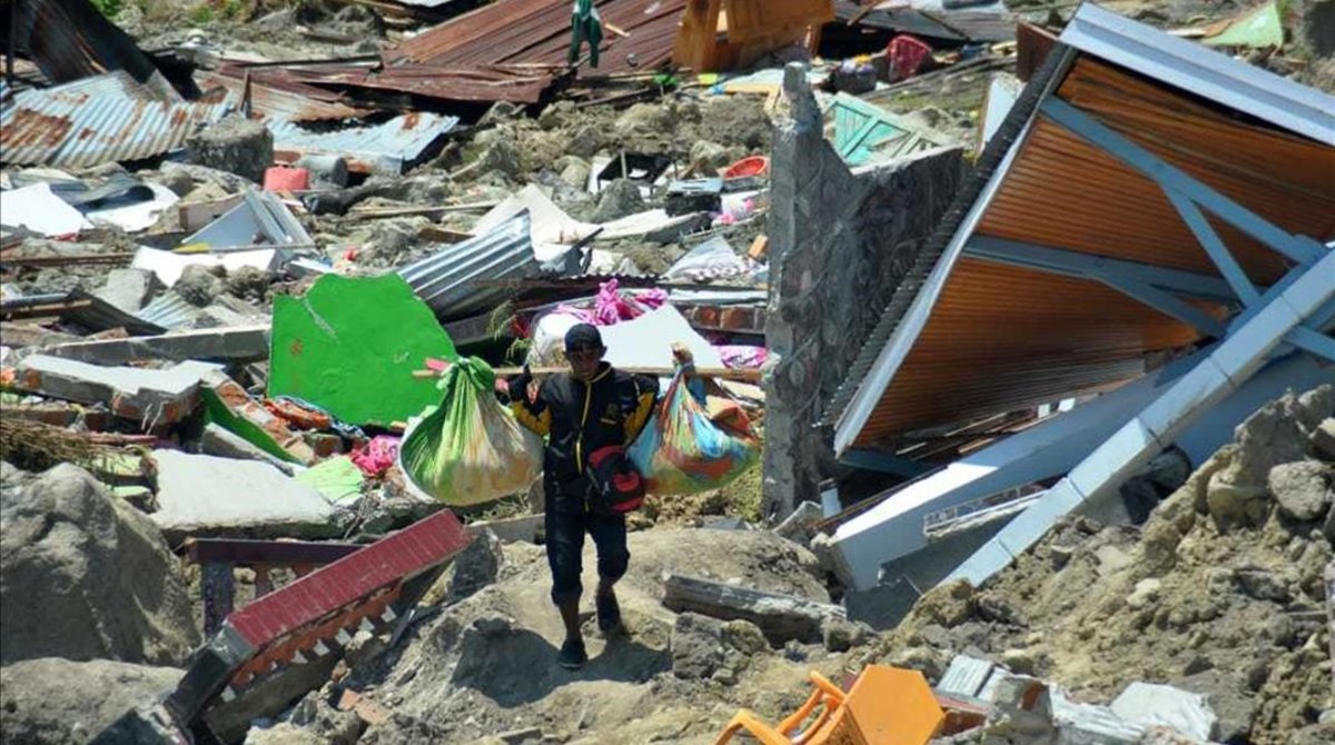 Un hombre carga objetos personales entre los escombros de un edificio derrumbado por el terremoto, en la ciudad indonesia de Palu.&#160;