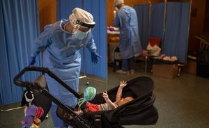 Una voluntaria de la ONG Open Arms juega con un niño de cuatro meses mientras espera a que su padre se haga un test PCR, en Vilafranca del Penedès.