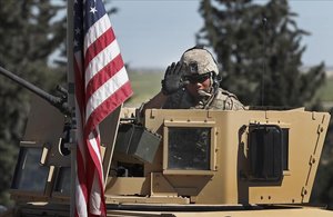 Un soldado de EEUU saluda desde un vehículo blindado en una carretera que conduce a la ciudad de Manbij, al norte de Siria. 