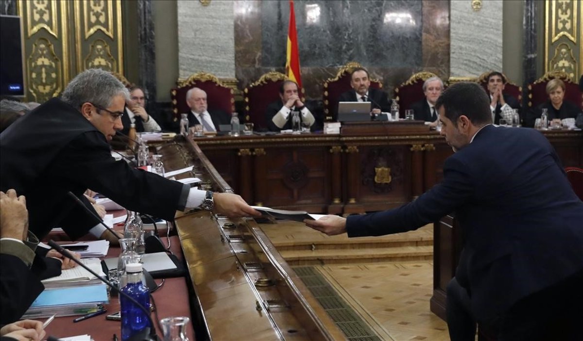 Francesc Homs intercambia un documento con Jordi Sánchez.