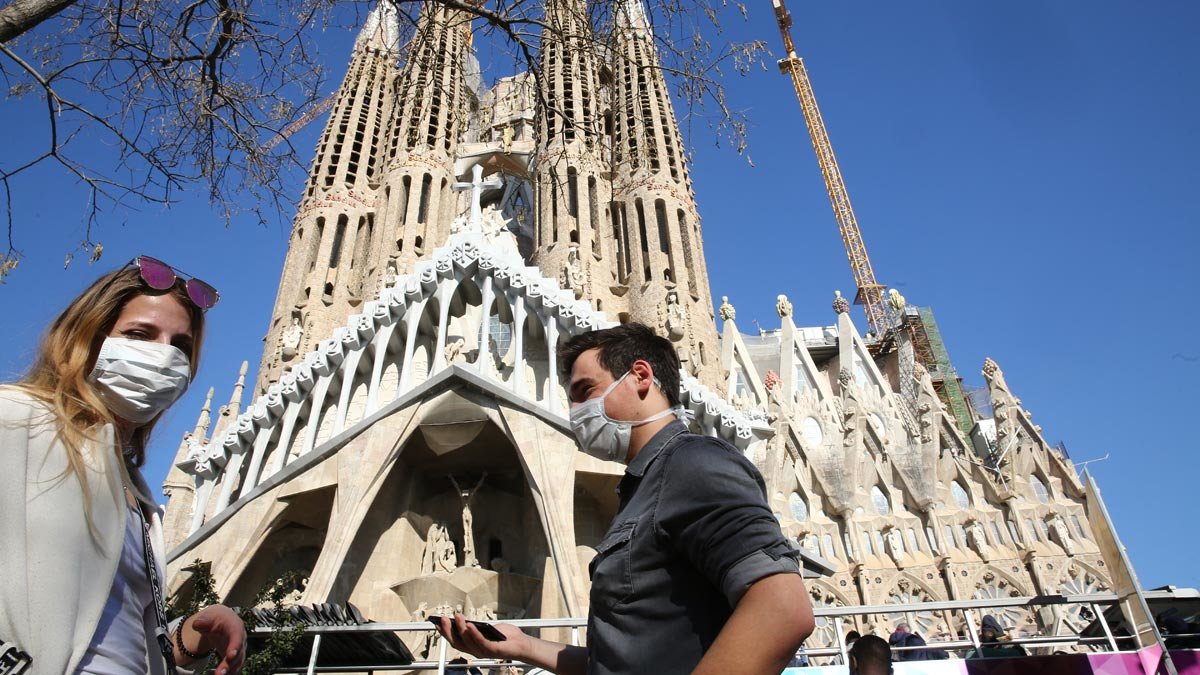 Dos turistas con mascarilla, ante la Sagrada Família de Barcelona.