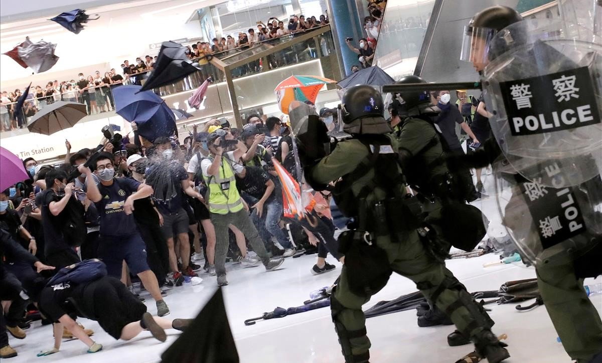 Manifestantes lanzan paraguas contra policías antidisturbios en un centro comercial de Hong Kong. 