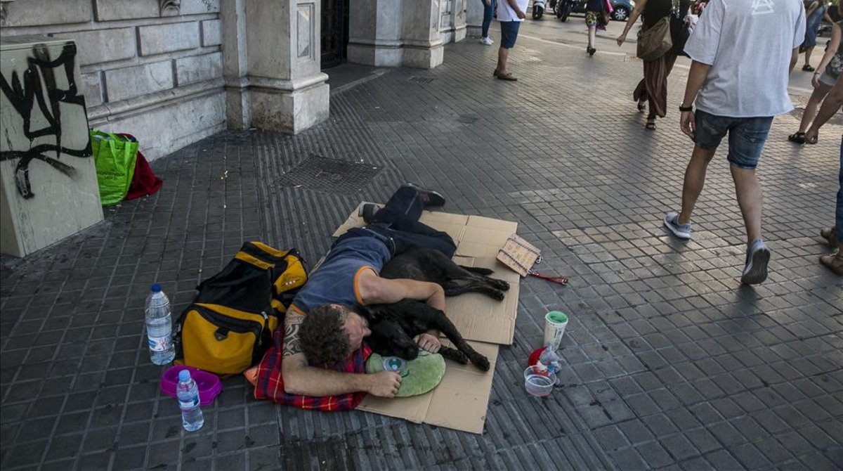 Un sintecho duerme en plena calle en &#160;la Rambla de Catalunya con Plaza de Catalunya.