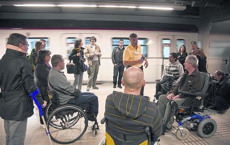 En el andén 8 Jesús Montesinos (polo amarillo) explica a unos discapacitados cómo utilizar la red de metro.