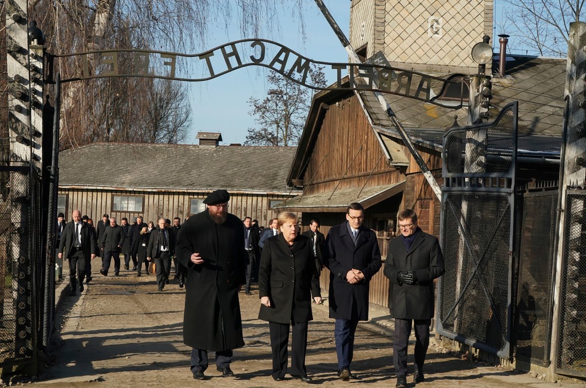 Angela Merkel cruza la puerta de entrada del campo de concentración de Auschwitz, bajo el siniestro cartel ’El trabajo os hará libres’.