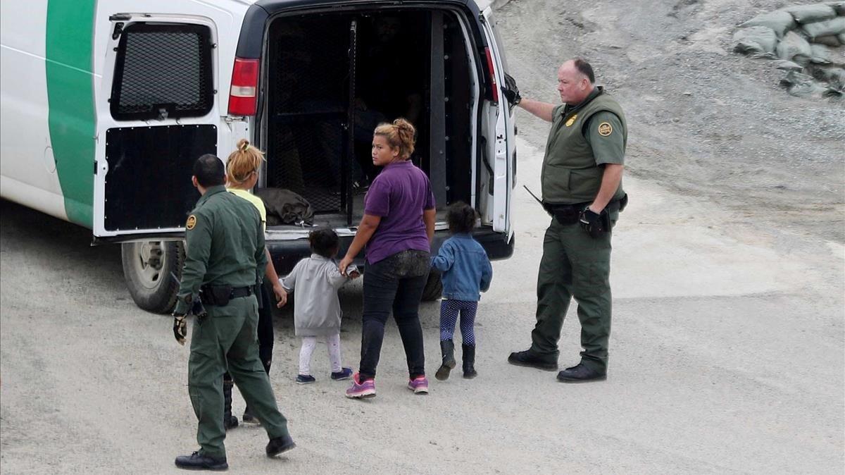 Oficiales migratorios de los EEUU detienen a una mujer y su hijo.