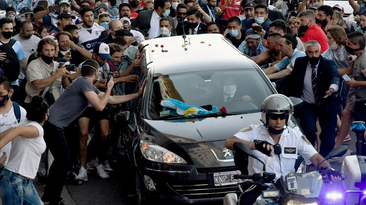 La multitud se agolpa ante el vehículo con feretro de Maradona.