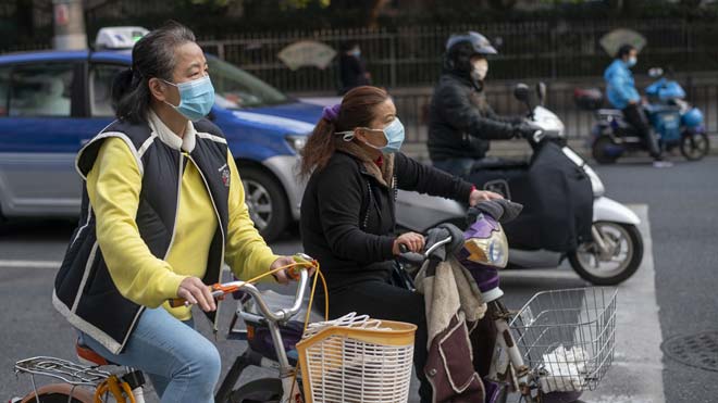 China eleva a 2.912 los fallecidos por el coronavirus. En la imagen, ciclistas protegidos con mascarillas en Shanghái.